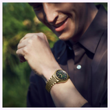 A person in a dark shirt looks down and smiles at their Seiko Luxe Watches Presage Classic Series HCC009 Limited Edition, admiring the renowned Japanese craftsmanship of the Seiko Luxe Watches brand, while blurred green foliage fills the background.