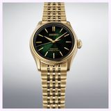 The Seiko Luxe Watches Presage Classic Series HCC009 Limited Edition wristwatch, featuring a gold case, green and black dial, gold hour markers, and a gold metal link band, exemplifies Japanese craftsmanship and is displayed against a light gray background.