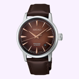Exuding timeless sophistication, the Seiko Luxe Watches Presage Cocktail Time HCB003 features a brown leather strap, a striking brown sunburst dial, rose gold hour markers and hands, and a date window at 3 o’clock. Presented against a light purple backdrop, this model from Seiko Luxe Watches beautifully highlights its refined craftsmanship.
