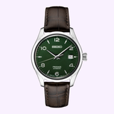 The Seiko Luxe Watches Presage Green Enamel Limited Edition SPB111 Men, featuring a striking green enamel dial, silver hour markers, a date window at 3 o’clock, and a brown leather strap, is elegantly showcased on a light purple background—a distinguished selection from Seiko Luxe Watches.