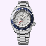 The Seiko Luxe Watches SPB519 Prospex Heritage Diver’s GMT in stainless steel features a silver dial, blue-and-silver rotating bezel, bracelet, three hands, date at 4 o’clock, and red GMT text on the dial.