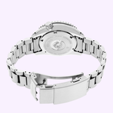 The Seiko Luxe Watches SPB519 PROSPEX HERITAGE DIVER'S GMT, a stainless steel dive watch, is shown with an open clasp revealing the engraved Seiko logo and wave design on the case back, displayed on a light purple background.