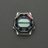 The Seiko Watches 5 Rotocall SMGG21 features a black and silver octagonal face with a white digital display and vibrant bezel labels, presented on a gray textured surface.
