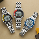 Three Seiko Watches 5 Rotocall SMGG21 digital watches by Seiko Watches, each with a metal band and bold red, yellow, or blue accents around the face, are displayed on a beige surface showing the same time and date.