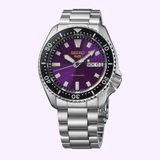A silver Seiko Watches 5 Sports HDB003 145th Anniversary Limited Edition wristwatch by Seiko Watches, featuring a metallic band, a purple dial with white markers, a black bezel, and a day-date display set to MON 6. The word “Automatic” appears in gold on the dial, capturing the SKX Series-inspired design of this exclusive limited edition timepiece.