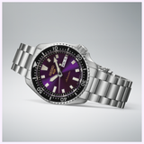 The Seiko Watches 5 Sports HDB003 145th Anniversary Limited Edition automatic wristwatch by Seiko Watches features a stainless steel band and a purple gradient dial with day and date display. Inspired by the renowned SKX Series, this limited edition timepiece showcases a black bezel with minute markers and is set against a light gray background.
