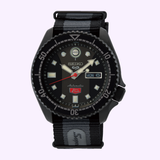 The Seiko Watches 5 Sports SKX series SRPJ75 LIMITED EDITION is a black automatic watch with a striped black/gray fabric strap, round black bezel, luminous markers, and a day-date window—Super Cub Limited Edition.