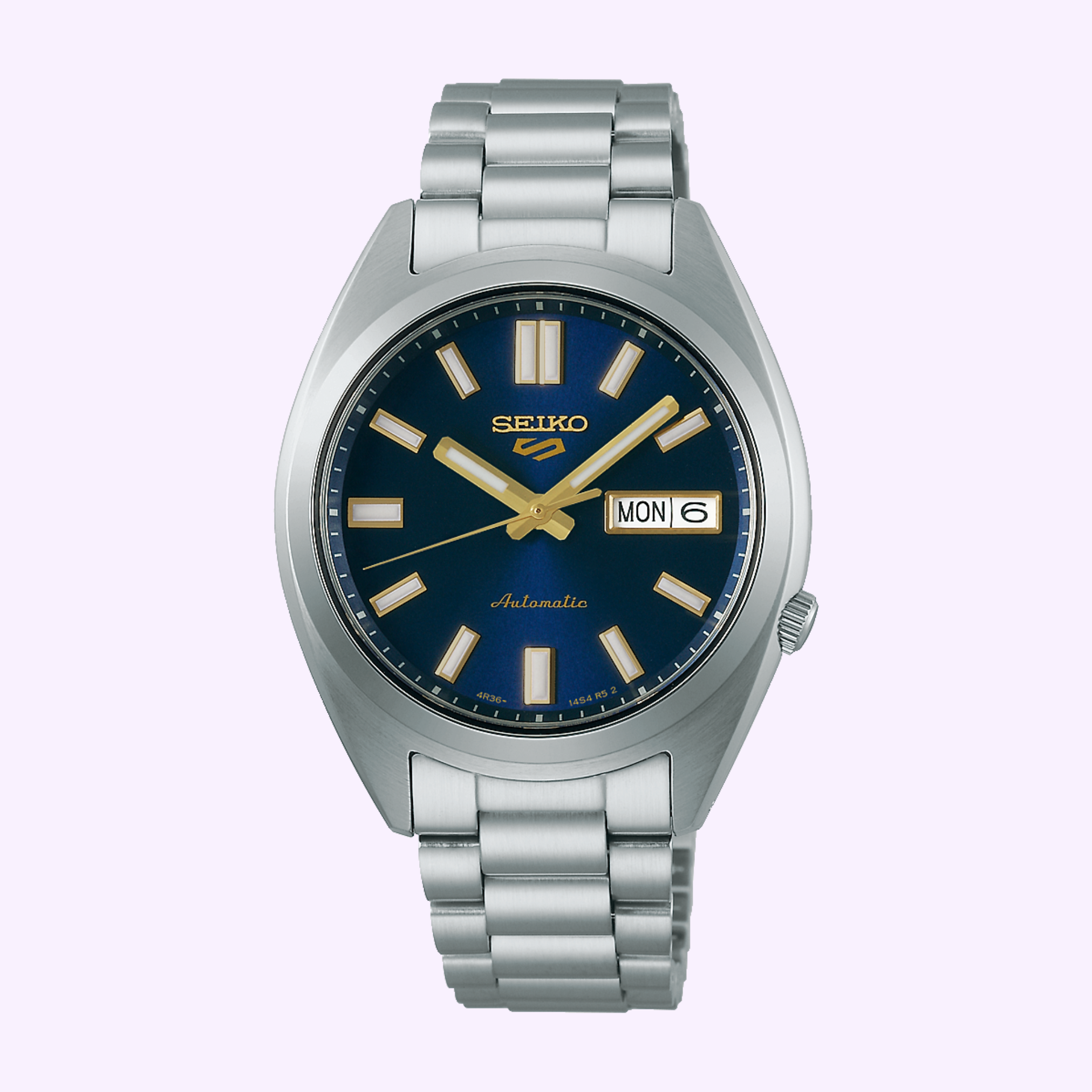 The Seiko Watches 5 Sports SNXS series SRPL55 features a gold stainless steel case, blue dial, gold and white hour markers, day-date at 3 o’clock, and automatic movement, shown on a light purple background.