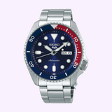 A Seiko Watches 5 Sports SRPD53 automatic watch by Seiko Watches, featuring a silver stainless steel band, blue dial with white markers, and a blue and red bezel. The watch displays the day and date as MON 6.