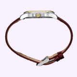 Side view of a Seiko Watches Essentials SUR360 men’s quartz watch by Seiko Watches, featuring a silver case, gold crown, and brown leather strap, isolated on a light purple background.