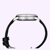Side view of the Seiko Luxe Watches Presage Cocktail Time Man SRPB43 with a black leather strap and silver case, round S-engraved crown, set against a light purple background.