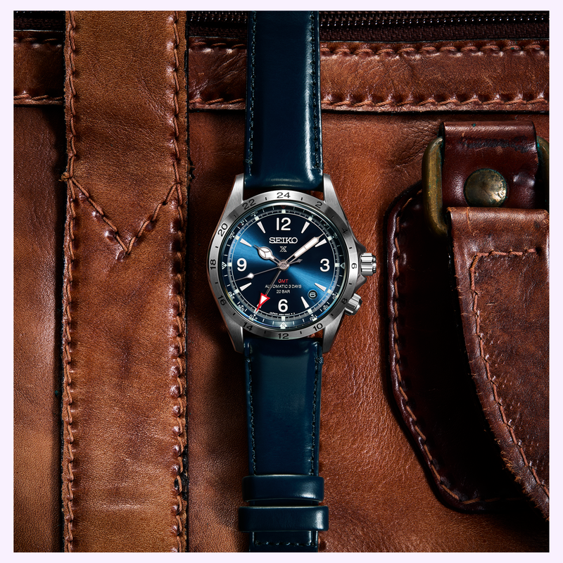 Seiko Prospex Alpinist GMT SPB377 with blue leather strap resting on brown leather travel bag