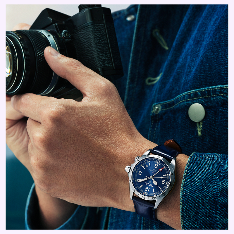 Man in blue denim jacket wearing the Seiko Prospex Alpinist GMT SPB377 with blue leather strap