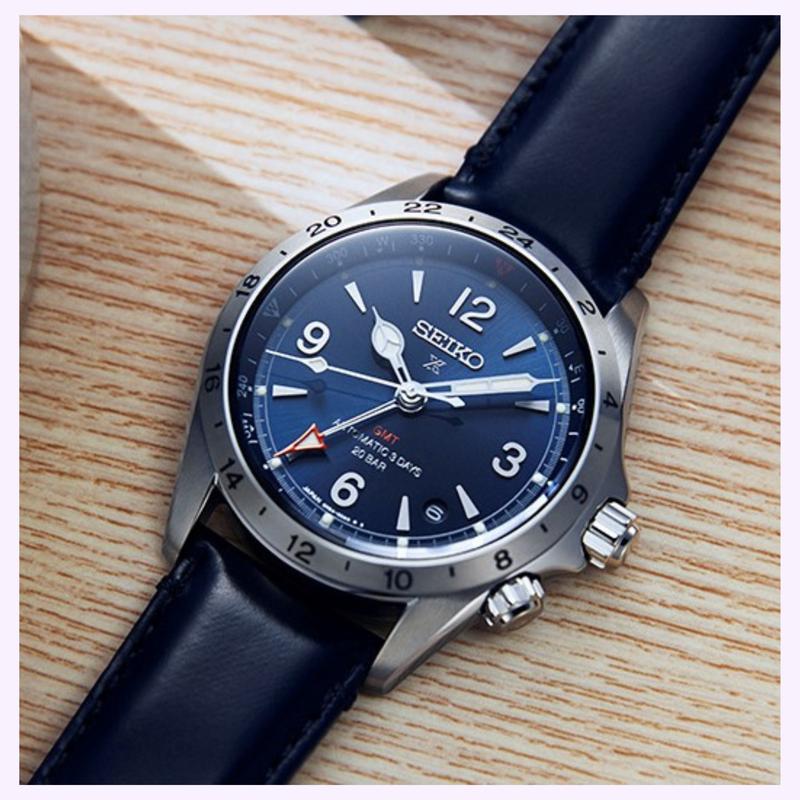 Seiko Prospex Alpinist GMT SPB377 blue dial close-up on wooden surface showing GMT hand and compass bezel
