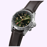 The Seiko Watches Prospex Alpinist HBC007 by Seiko Luxe Watches, featuring a green dial with gold markers, a brown leather strap, silver bezel, GMT hand, and reliable Seiko quartz movement, is displayed at an angle against a light purple background.
