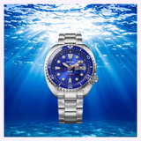 The Seiko Watches Prospex HBB002 Limited Edition by Seiko Luxe Watches features a striking blue face and a silver metal band, showcased at the center of a sunlit underwater scene, with beams of light streaming through the water to highlight its precision automatic mechanical movement.