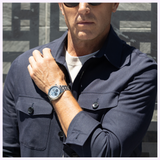 A man wearing a Seiko Watches Prospex Speedtimer HBD001 featuring a silver chronograph watch with a blue dial and a metal link bracelet.