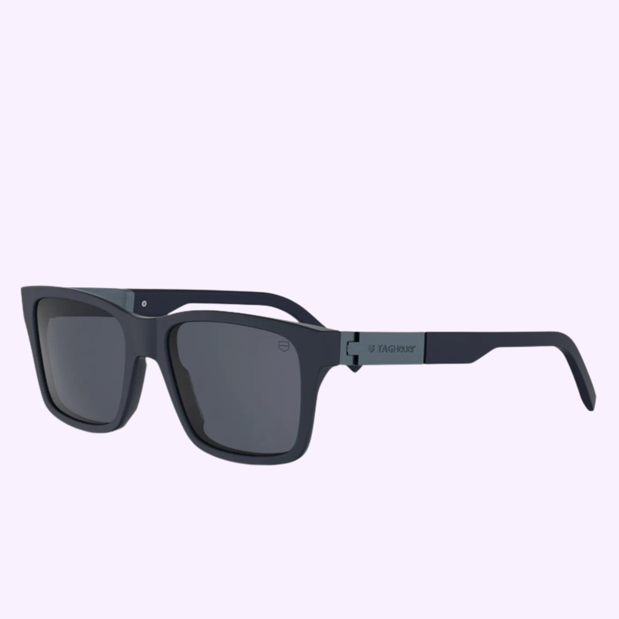 Tag Heuer Optical TH40057I 5490V black square-frame sunglasses with dark lenses and a logo on the left temple, shown on a light purple background—offered by an authorized Miami dealer.