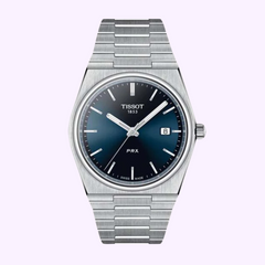 The Tissot T1374101104100 PRX Bracelet 40mm men’s watch by Tissot Watches features a blue gradient dial, silver markers and hands, date at 3 o’clock, and a brushed stainless steel bracelet, shown on a light background.