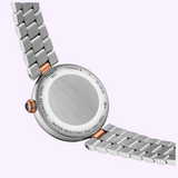 The reverse side of a silver-toned Tissot Watches Desir 29.6mm T1522232203600 watch with a metal link bracelet and a small blue accent on the winding crown.
