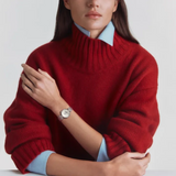 A woman wearing a red turtleneck sweater and a Tissot Watches Desir T1522231103600 wristwatch with a white dial.