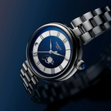 Tissot Watches Desir T1522231149300 silver-tone watch with a dark blue, glittered dial, Roman numeral hour markers, and a moon phase display on a stainless steel link bracelet.