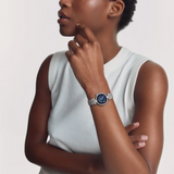 A person wearing a silver-toned Tissot Watches Desir T1522231149600 moonphase watch with a round, dark blue face on their wrist.