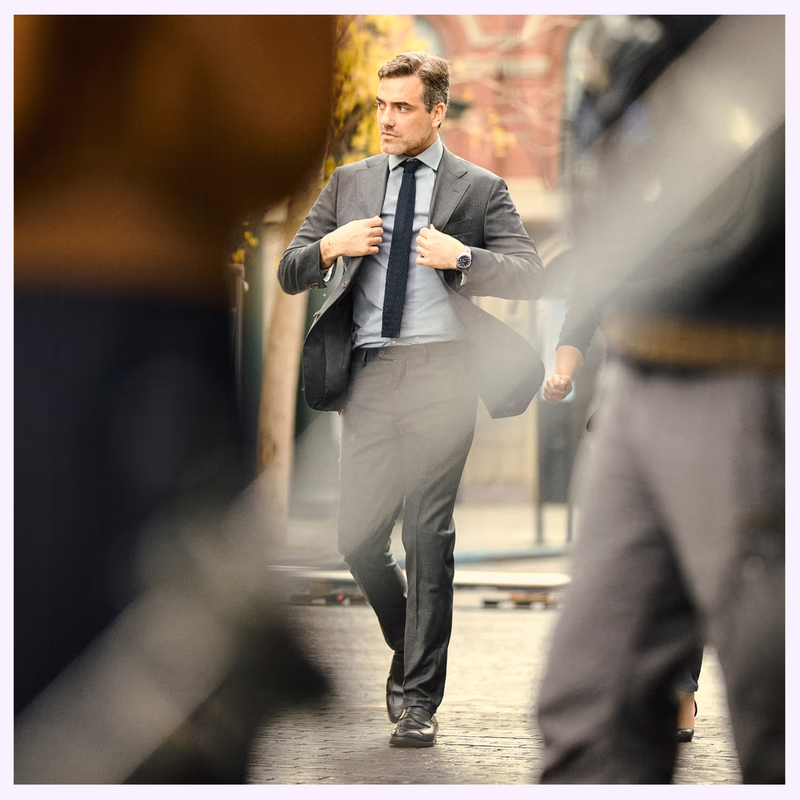 Man in a suit walking outdoors, adjusting his jacket to reveal the Tissot Gentleman 38mm T1658071104100 on his wrist