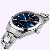 The Tissot Watches Gentleman 38mm (T1658071104100) features a blue dial with silver hour markers and hands, date at 3 o'clock, and a stainless steel bracelet, shown from the side against a light background.
