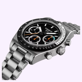 The Tissot Watches PR516 41mm T1494592105100 by Tissot Watches is a stainless steel chronograph wristwatch, showcased at an angle against a light purple background. It features a striking black chronograph dial with colorful subdials and is paired with a sleek metal link bracelet. Housed in a durable stainless steel case, this classic timepiece relies on the precision and reliability of Swiss manual winding movement.