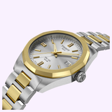 The Tissot Watches PRC 100 Solar 34mm (model T1518222203100) features a sophisticated silver and gold stainless steel design, a round face with date display, and a metal strap. Showcasing precise Swiss quartz solar technology by Tissot Watches, this elegant wristwatch stands out against a pale background with its timeless style.