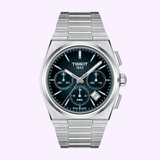 The Tissot Watches PRX 42mm T1374271104101 from Tissot Watches features a silver stainless steel bracelet, a striking blue dial with three subdials, and a date window at 4 o’clock. Crafted with durable sapphire crystal, this elegant Swiss automatic chronograph combines classic style and precision engineering, beautifully presented against a light purple background.