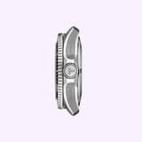 Side view of the Tissot Watches Seastar 2000 44mm T1209071105100, featuring a silver case, ridged bezel, textured crown, and metal lugs, photographed on a light purple background.