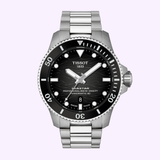 The Tissot Watches Seastar 2000 44mm T1209071105100 by Tissot Watches is a premium diving watch crafted from stainless steel, featuring a black dial with silver hour markers, a date window at 6 o’clock, and a rotating bezel. Powered by Swiss automatic movement, this sophisticated wristwatch is displayed against a light purple background.
