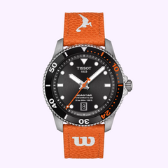 The Tissot Watches Seastar Wilson WNBA T1208071705100 features a black dial with orange accents, an orange textured strap with a white bird and W logo, plus a black bezel with orange numerals—the ultimate women’s basketball watch by Tissot Watches.