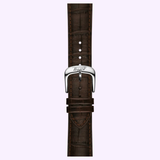 Close-up of a brown leather watch strap with prominent stitching and a silver buckle engraved with the Tissot Watches logo, set against a light purple background. This sophisticated detail is part of the Tissot Watches Visodate 39mm T1574071603100, a refined Swiss automatic timepiece known for its reliable Powermatic 80 movement.