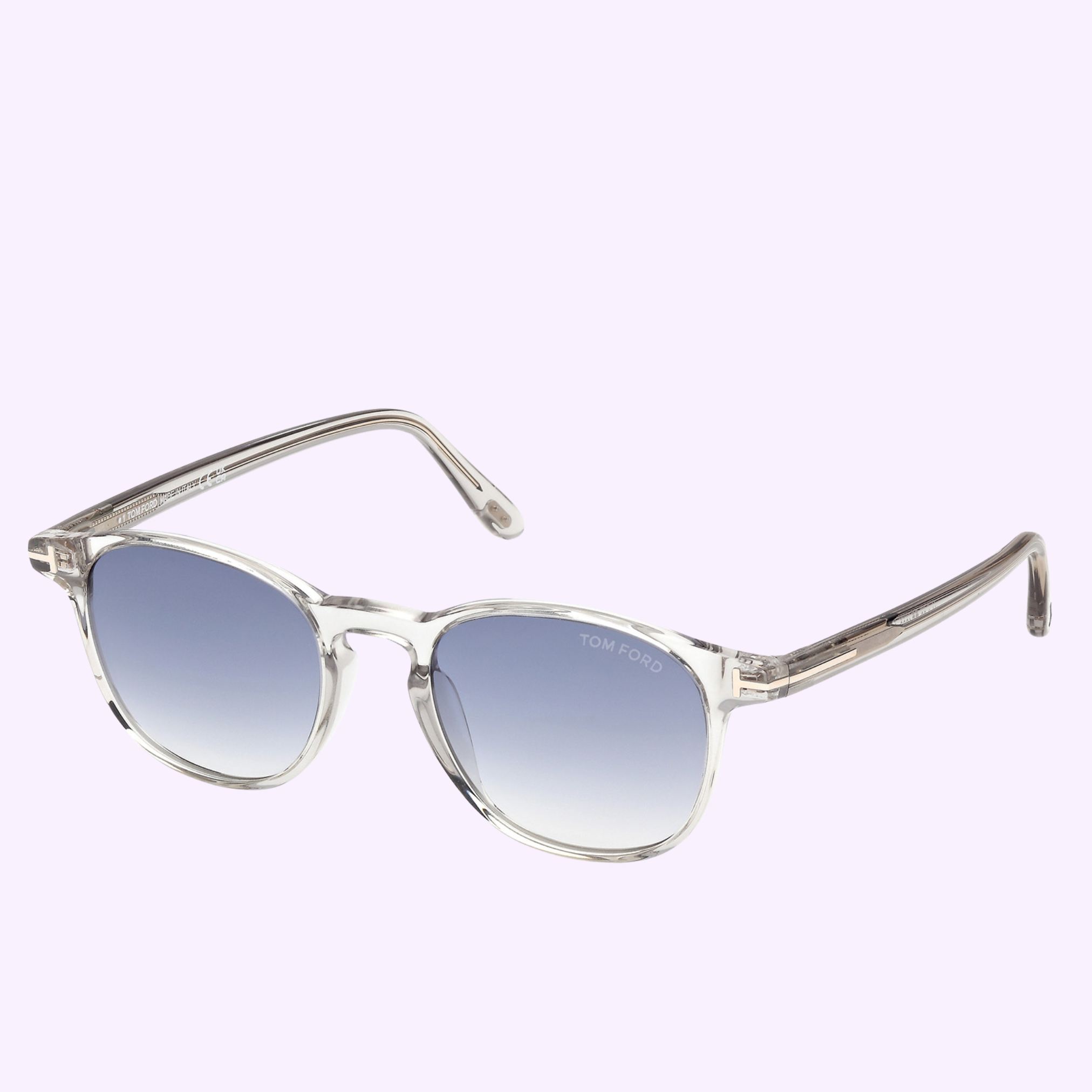 Tom Ford Sunglasses FT1302 5020W feature clear frames, round gradient blue lenses, and signature TOM FORD branding on the right lens, shown against a light purple background for a stylish Miami-ready look.