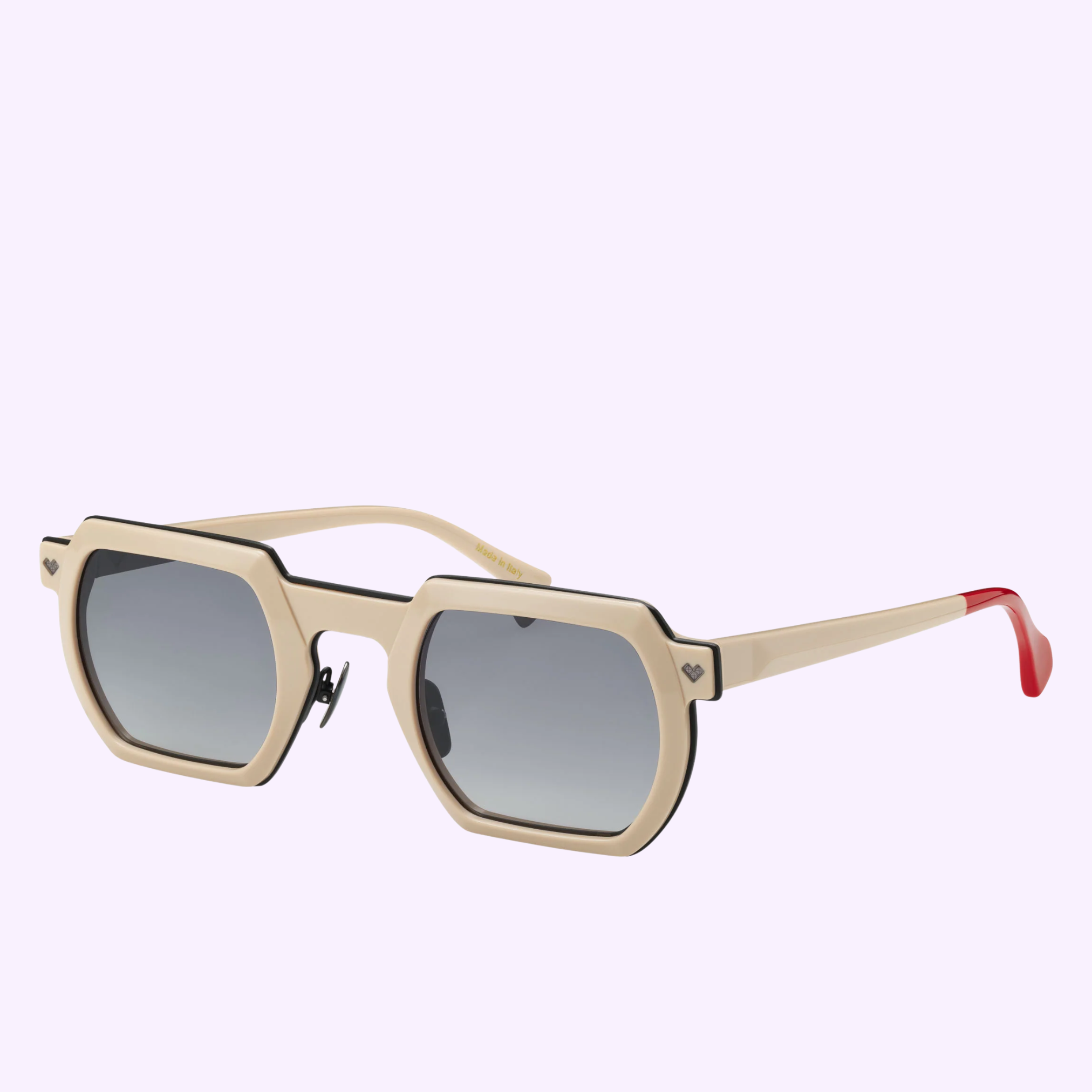 The Tracker TK4 by Vysen Sunglasses features beige geometric frames handcrafted in Italy with black trim, dark gradient lenses, and subtle red accents on the arm tips, shown against a light purple background.