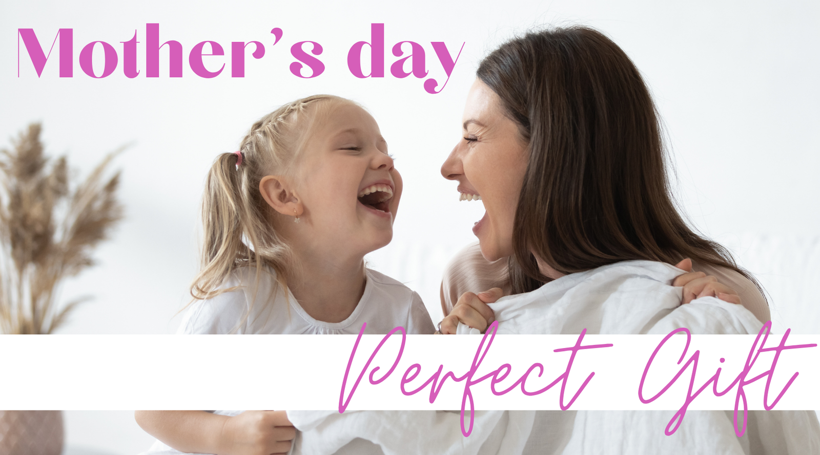 A smiling woman and young girl laugh together on a couch, holding a white blanket. Text reads Mother’s day at the top and Perfect Gift at the bottom in pink script. Dried flowers are blurred in the background.