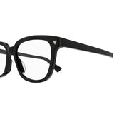 Close-up of the left half of the sophisticated Bottega Veneta BV1229OA-001 52 Optical Frame for women, showing a black acetate construction with clear lenses, a distinctive small gold triangular detail at the front corner, and Bottega Veneta engraved on the temple.