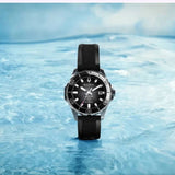 A Bulova Watches Marine Star 98B465, featuring a sleek black strap, floats on the surface of clear blue water against a softly blurred blue sky, perfectly showcasing this luxury men’s timepiece from Bulova Watches.