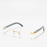 The Cartier Optical CT0052O-010 53 unisex optical frame, featuring rimless luxury design with gold accents and gray arms, is displayed on a white surface with a soft shadow, highlighting its sophisticated appeal.