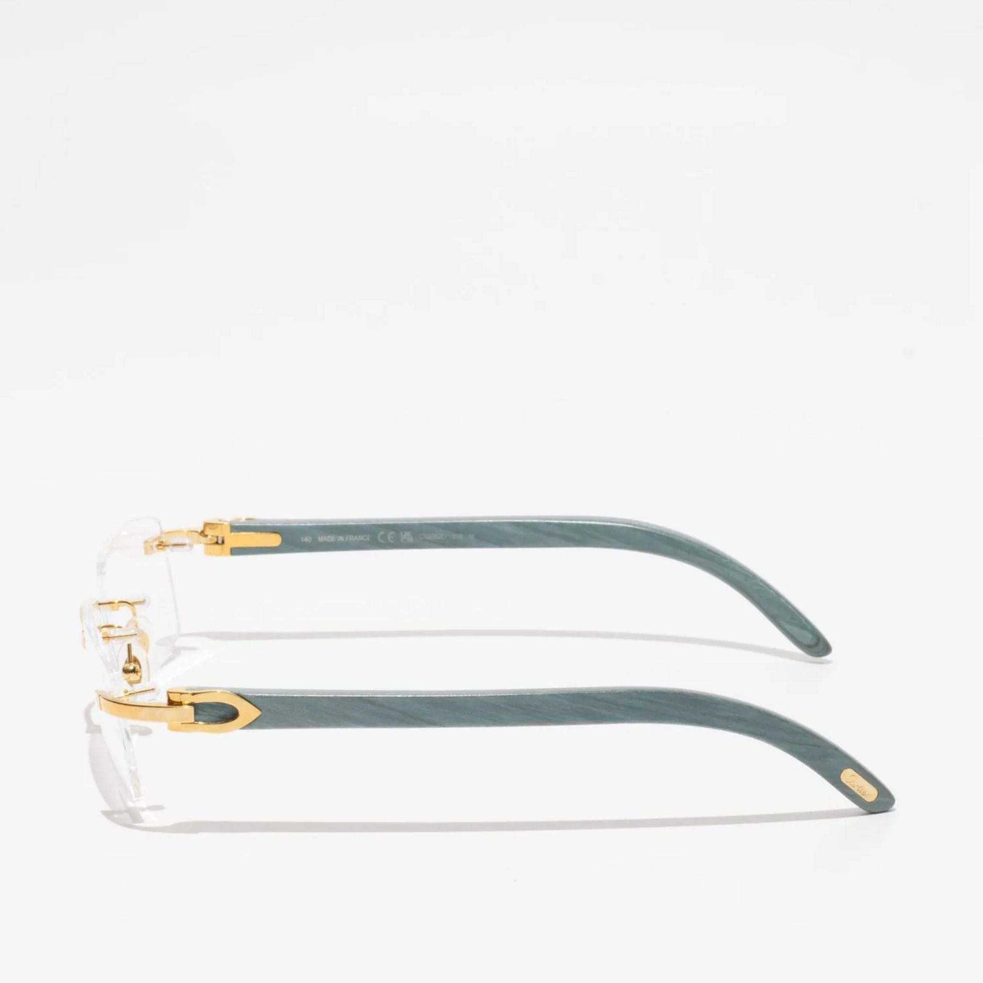 Cartier CT0052O-010 unisex optical frame shown from the side, revealing green-tinted temples, gold-tone bridge, and hinges—luxury eyewear with premium metal construction and adjustable nose pads