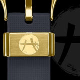 Here is a rewritten version using your product data: A detailed close-up of the gold clasp on the CASIO G-SHOCK ANALOG-DIGITAL GBM2100RH-1A reveals a circular symbol engraved atop its textured black strap. A larger, more subtle version of this emblem appears in the background, emphasizing the exclusive Rui Hachimura Signature design by G-Shock Watches. This innovative timepiece also features advanced Tough Solar technology.