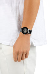 A person in a white textured shirt and white pants, hand relaxed by their side, wears the Rado Watches R30012152 Centrix Automatic Open Heart with an antimagnetic Nivachron hairspring.