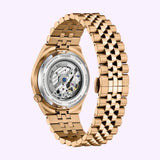 A Citizen Watches TSUYOSA 60 NK0023-57L automatic watch in gold with a metal link band is shown from the back, revealing its exposed mechanical movement and engraved case details.