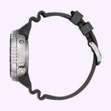 Side view of the Citizen Watches Promaster Dive E365 BN1024-01Z wristwatch, featuring a silver case, black ridged bezel, black wavy rubber strap, and silver buckle—displayed against a light purple background. This Eco-Drive dive watch by Citizen Watches is crafted to meet the rigorous demands of professional divers.