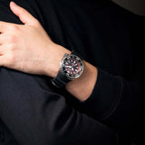 A person wearing a black long-sleeve shirt crosses their arms, displaying the Citizen Watches Promaster Dive E365 BN1024-01Z on their wrist. This professional diver watch by Citizen Watches features a bold round face with prominent markers and a distinctive black and silver design that exudes confidence.