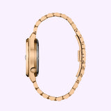 Here is a rewritten version of the sentence using your product data: Side view of the Citizen Watches TSUYOSA 60 NK0023-57L, an automatic gold watch with a round face and linked bracelet, featuring a vivid blue sunray dial, displayed against a light lavender background.