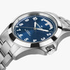 A close-up of the Hamilton Watches Khaki Field King Day-Date 40mm H64475140 shows a blue dial with white numerals, silver hands, day-date windows, polished bezel, and metal band—reflecting Miami style.